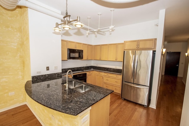 kitchen featuring black appliances, wood finished floors, light brown cabinetry, and a sink