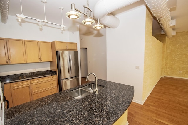 kitchen with dark stone countertops, light wood finished floors, freestanding refrigerator, and a sink