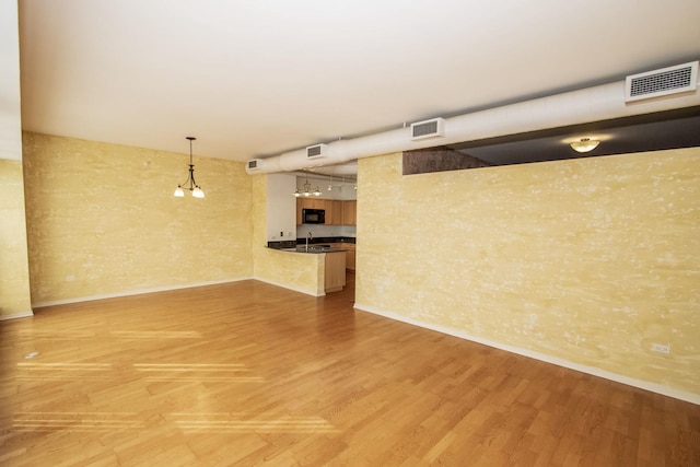 unfurnished room featuring light wood-type flooring, visible vents, and a sink