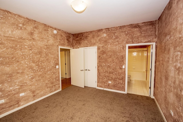 unfurnished bedroom featuring baseboards, ensuite bathroom, and carpet