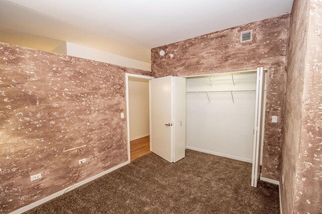 unfurnished bedroom featuring visible vents, baseboards, carpet, and a closet