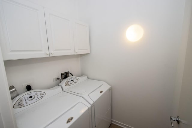 clothes washing area featuring washing machine and dryer and cabinet space