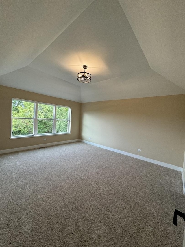 carpeted empty room with visible vents, baseboards, lofted ceiling, and an inviting chandelier