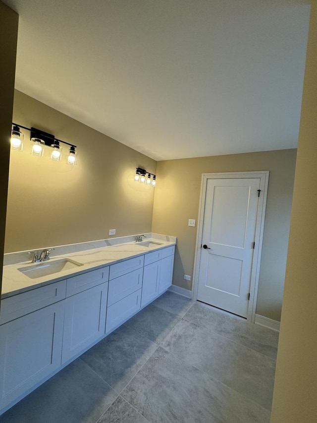 full bath featuring double vanity, baseboards, and a sink