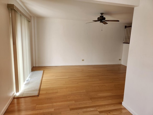 spare room featuring baseboards, light wood-style floors, and ceiling fan