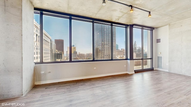 unfurnished room with a city view, visible vents, and wood finished floors