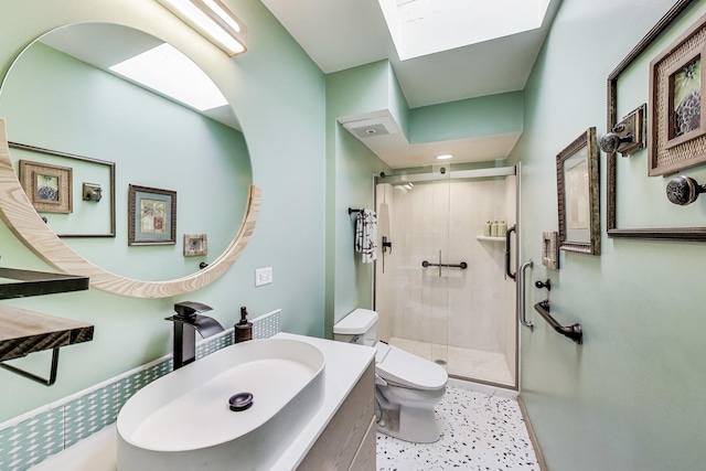 bathroom with vanity, toilet, a shower stall, and a skylight