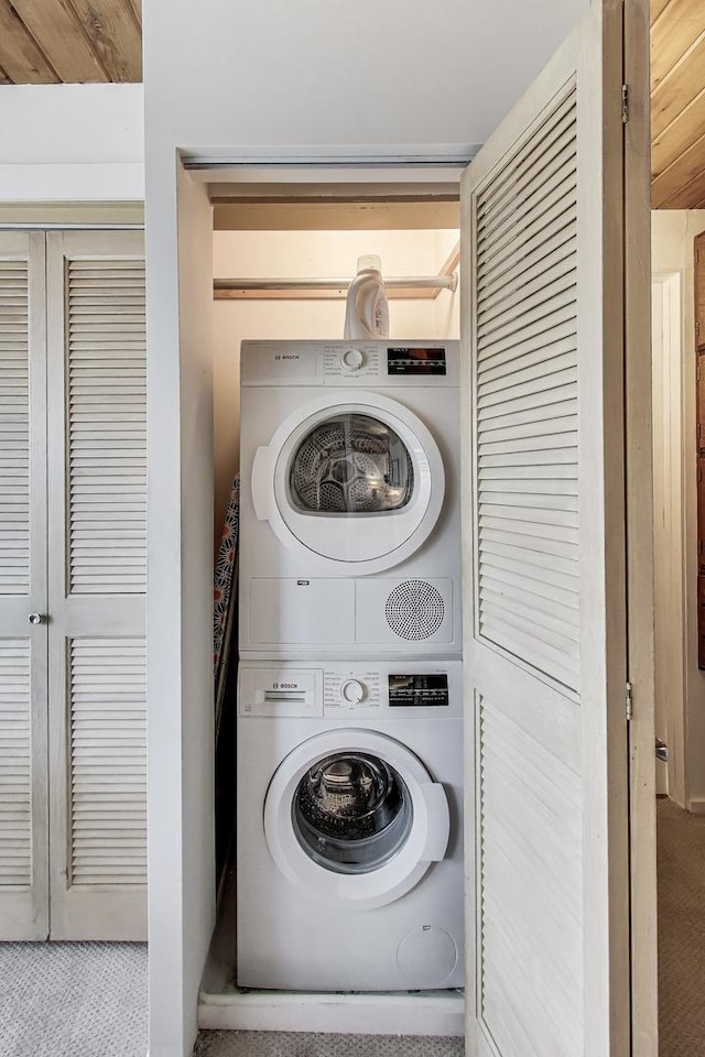 washroom featuring laundry area, stacked washer / dryer, and carpet
