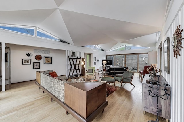 living area with vaulted ceiling and light wood-type flooring