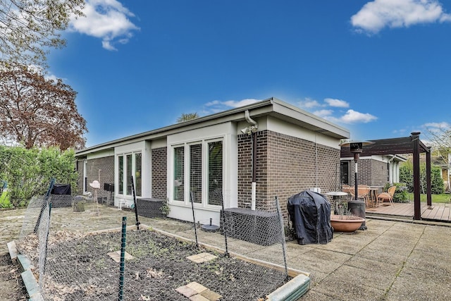 view of home's exterior featuring brick siding, a pergola, and a deck