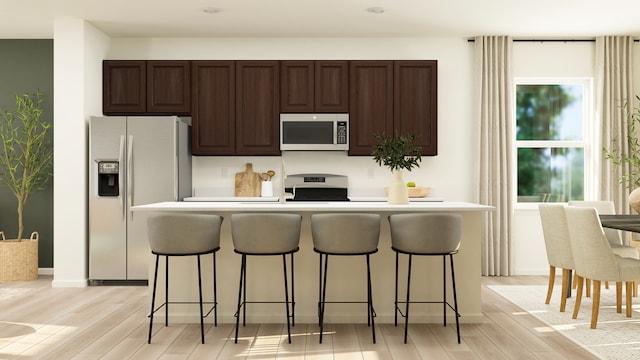 kitchen featuring stainless steel microwave, a kitchen breakfast bar, white fridge with ice dispenser, and stove