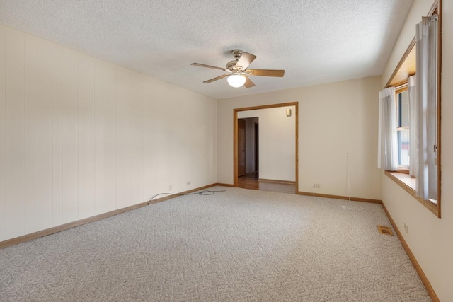 spare room with a textured ceiling, light colored carpet, visible vents, and ceiling fan