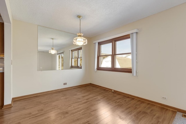 empty room with baseboards, visible vents, a textured ceiling, and light wood-style floors