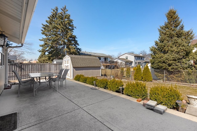 view of patio with a storage unit, a fenced backyard, outdoor dining area, and an outdoor structure