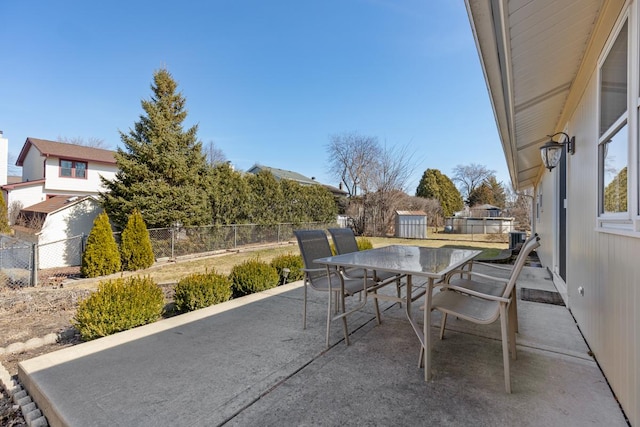 view of patio / terrace featuring a storage unit, outdoor dining area, an outdoor structure, and a fenced backyard