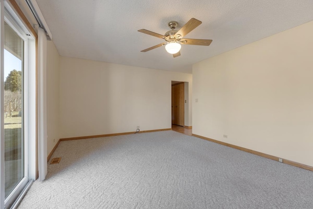 unfurnished room with visible vents, light carpet, a ceiling fan, a textured ceiling, and baseboards