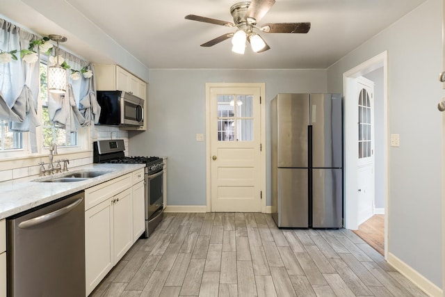 kitchen featuring stainless steel appliances, light wood-type flooring, ceiling fan, and a sink