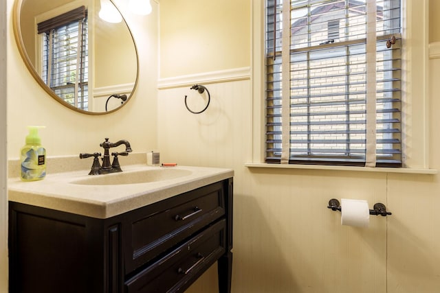 bathroom with vanity, a healthy amount of sunlight, and wainscoting