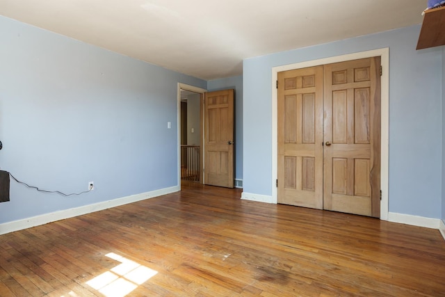 unfurnished bedroom featuring a closet, baseboards, and hardwood / wood-style flooring