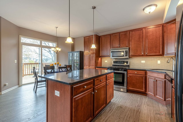 655 N Fox Trl, Round Lake, IL 60073 - kitchen with appliances with stainless steel finishes, wood-type flooring, backsplash, a sink, and a kitchen island