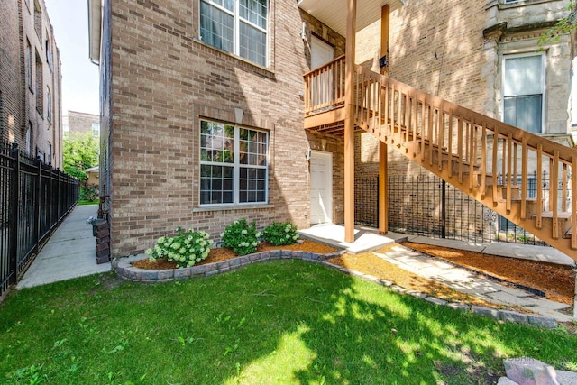 entrance to property featuring a yard, brick siding, and fence