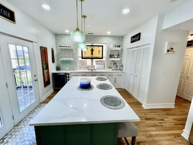 kitchen with open shelves, a kitchen island, light wood-style flooring, and recessed lighting