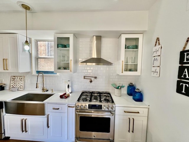 kitchen featuring tasteful backsplash, stainless steel gas range, wall chimney range hood, and a sink