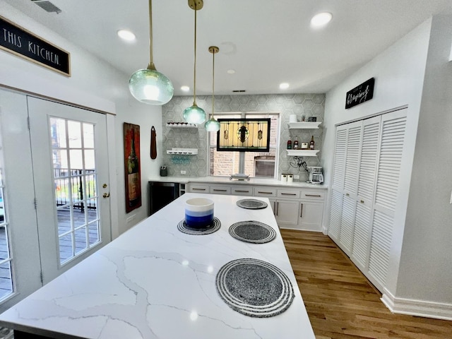 kitchen featuring open shelves, decorative light fixtures, wood finished floors, and backsplash