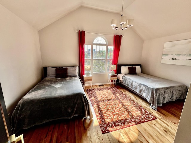 bedroom with a chandelier, wood finished floors, and vaulted ceiling