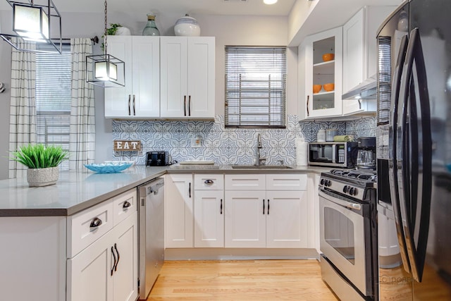 kitchen featuring a sink, stainless steel appliances, a peninsula, and white cabinets