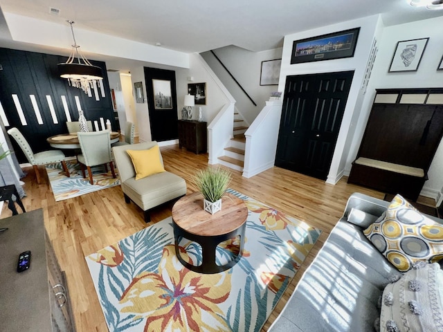 living area with visible vents, baseboards, a chandelier, stairs, and wood finished floors