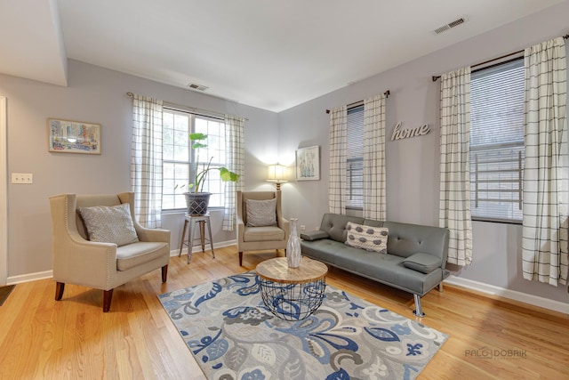 living area featuring visible vents, baseboards, and wood finished floors