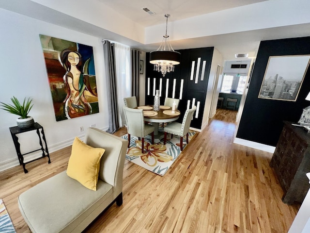 dining space featuring visible vents, baseboards, a notable chandelier, and wood finished floors