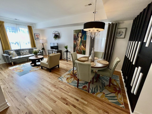 dining area featuring light wood-style floors, a notable chandelier, and visible vents