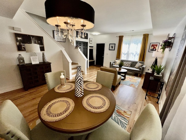 dining area featuring a notable chandelier, stairway, and wood finished floors