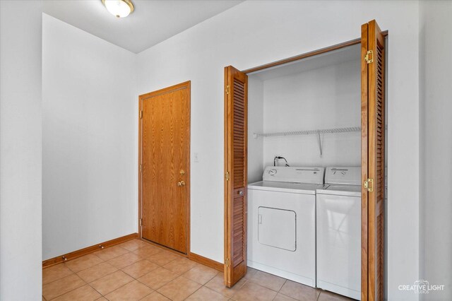 washroom with separate washer and dryer, laundry area, light tile patterned flooring, and baseboards