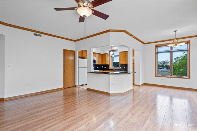 kitchen featuring brown cabinetry, freestanding refrigerator, dark countertops, open floor plan, and a wealth of natural light