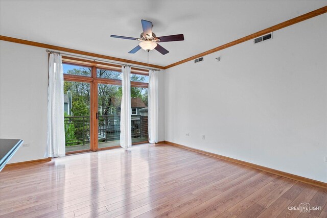 spare room featuring crown molding, a ceiling fan, light wood-style flooring, and visible vents