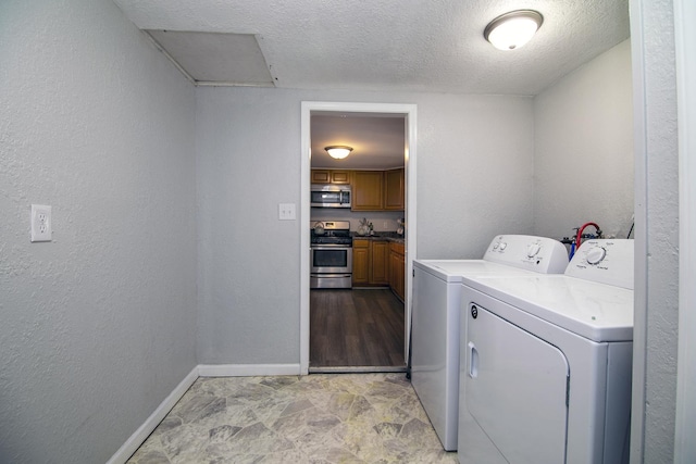 washroom with a textured ceiling, baseboards, washing machine and clothes dryer, laundry area, and a textured wall