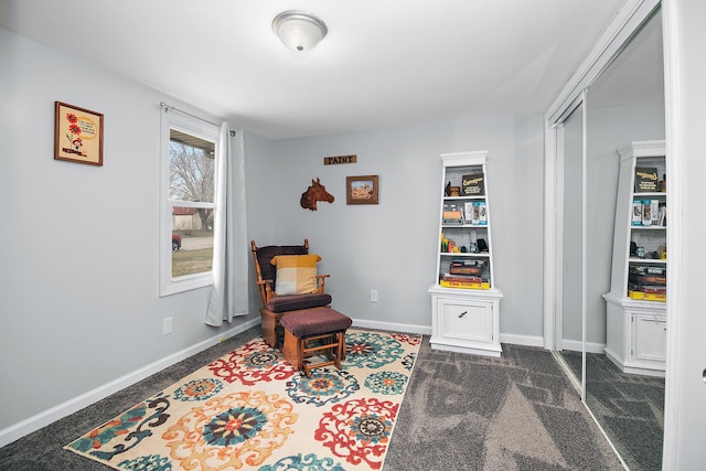 sitting room featuring baseboards and dark colored carpet