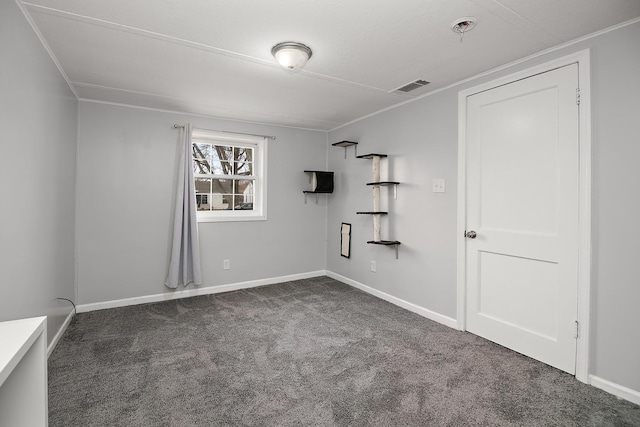 carpeted empty room with visible vents, crown molding, and baseboards