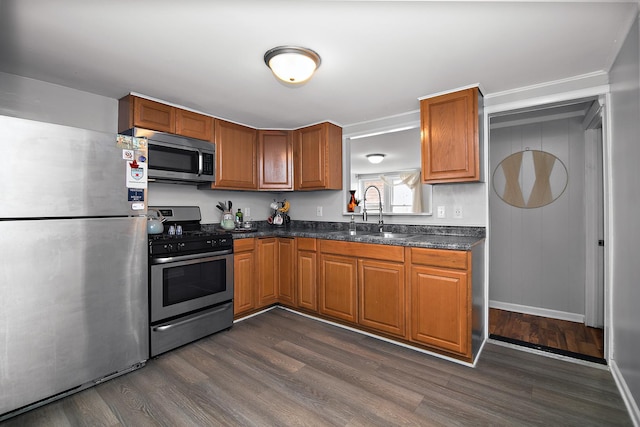 kitchen featuring a sink, dark countertops, dark wood-type flooring, and stainless steel appliances