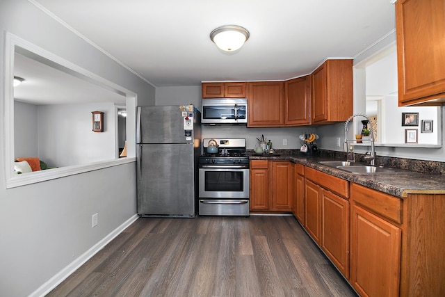 kitchen featuring brown cabinets, a sink, appliances with stainless steel finishes, baseboards, and dark wood-style flooring