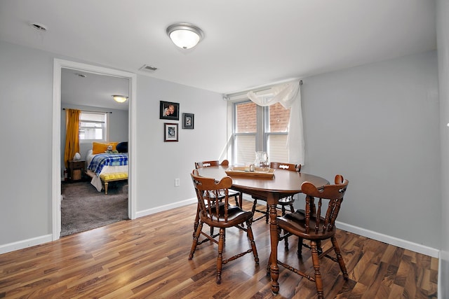 dining space with wood finished floors, visible vents, and baseboards