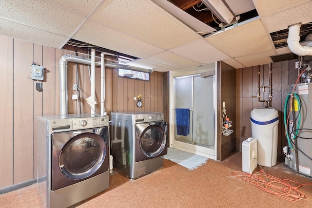 laundry room featuring water heater, wooden walls, laundry area, and washing machine and clothes dryer