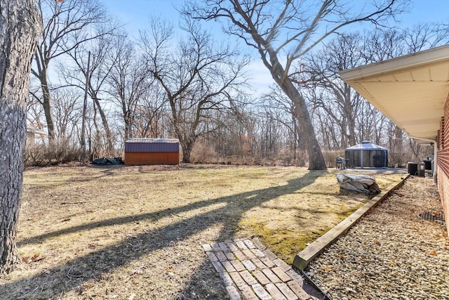 view of yard featuring a storage shed, central AC unit, and an outdoor structure