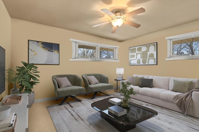 living area featuring baseboards and a ceiling fan