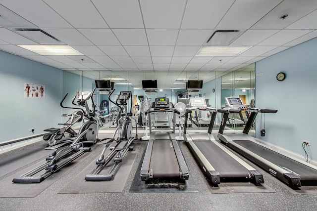 exercise room with visible vents, a paneled ceiling, and baseboards