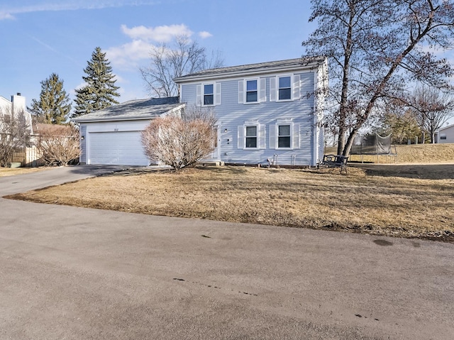 colonial home featuring an attached garage, concrete driveway, and a trampoline