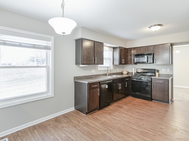 kitchen featuring dark brown cabinets, black appliances, light wood-style floors, and a sink